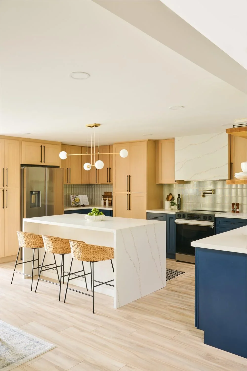 Kitchen with a white waterfall island and light wood-look flooring