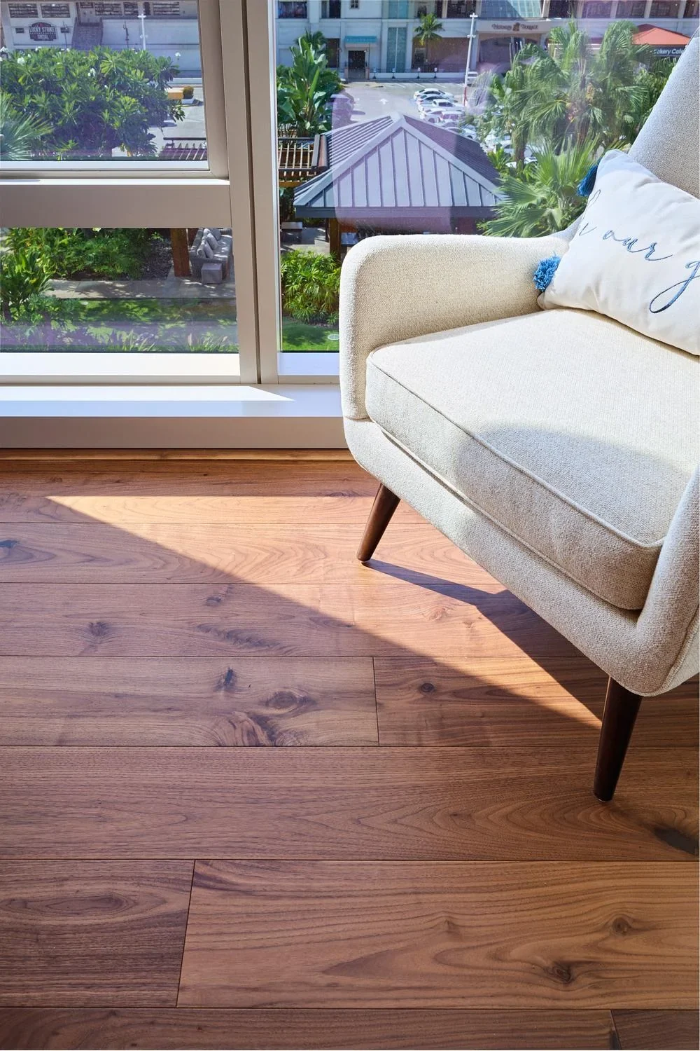 Close-up of walnut hardwood planks in afternoon sun beside a window